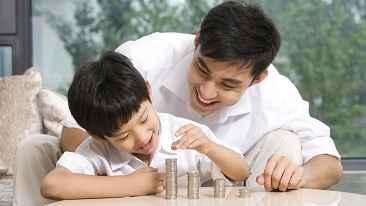 A boy stacking a coin with a man behind him