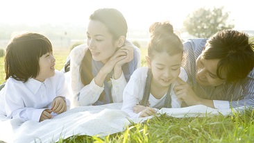 A family of four lying on the field talking