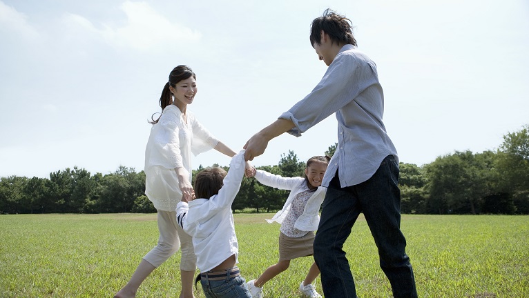 A family of four playing on a grass field