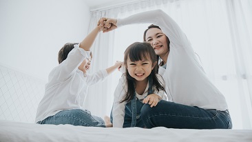 A family of three playing in the bedroom