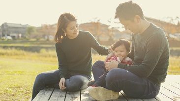 A family of three sitting on a field