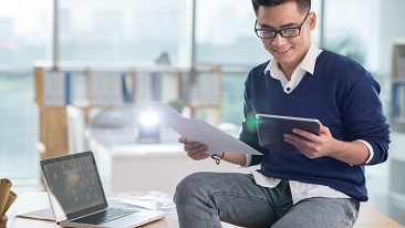 A guy looking at a tablet and a document