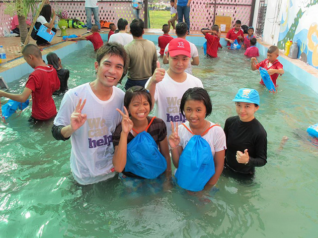 A volunteer and students smiling to the camera