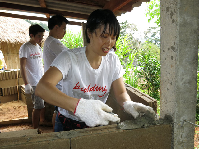 A volunteer applying cement to the bricks