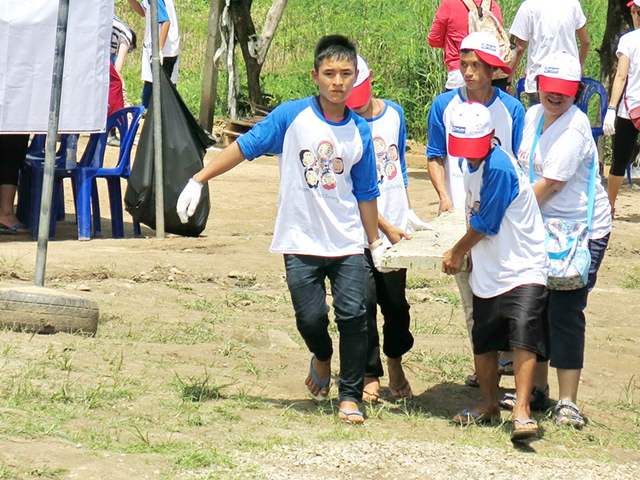 Five volunteers carrying a concrete plank