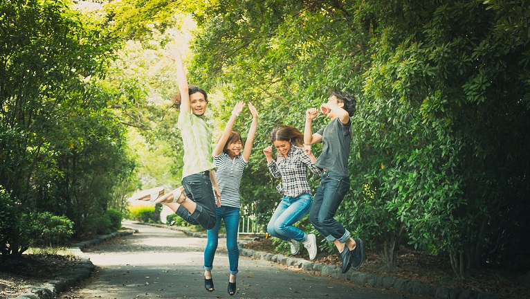 Four people jumping on road