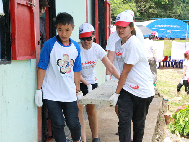 Four volunteers carrying a concrete plank