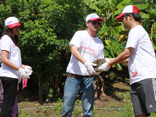Three volunteers passing two bricks