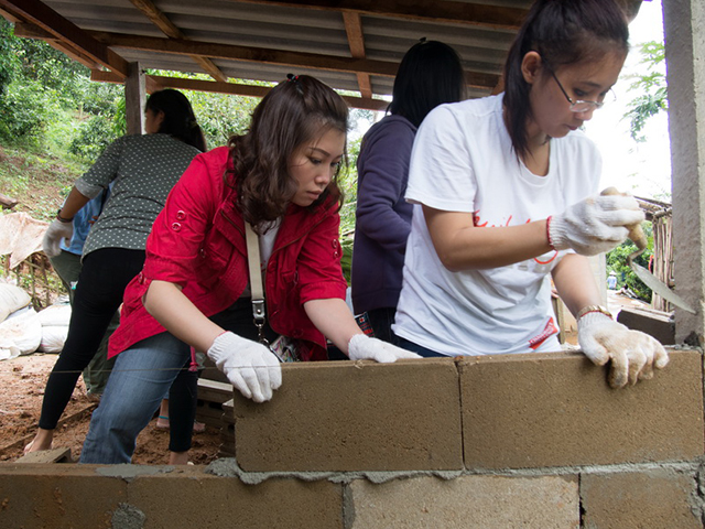 Two volunteers putting bricks on cement