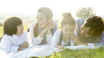 A family of four lying on the field talking