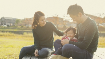 A family of three sitting on a field