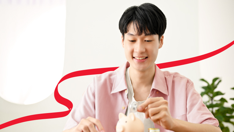A girl putting a coin into a piggybank while her friend hold it